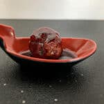 Meatball with brandy blackberry sauce in cocktail spoon.