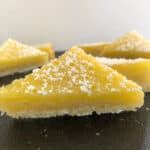 Lemon Bars cut into triangles and topped with a dusting of powdered sugar.