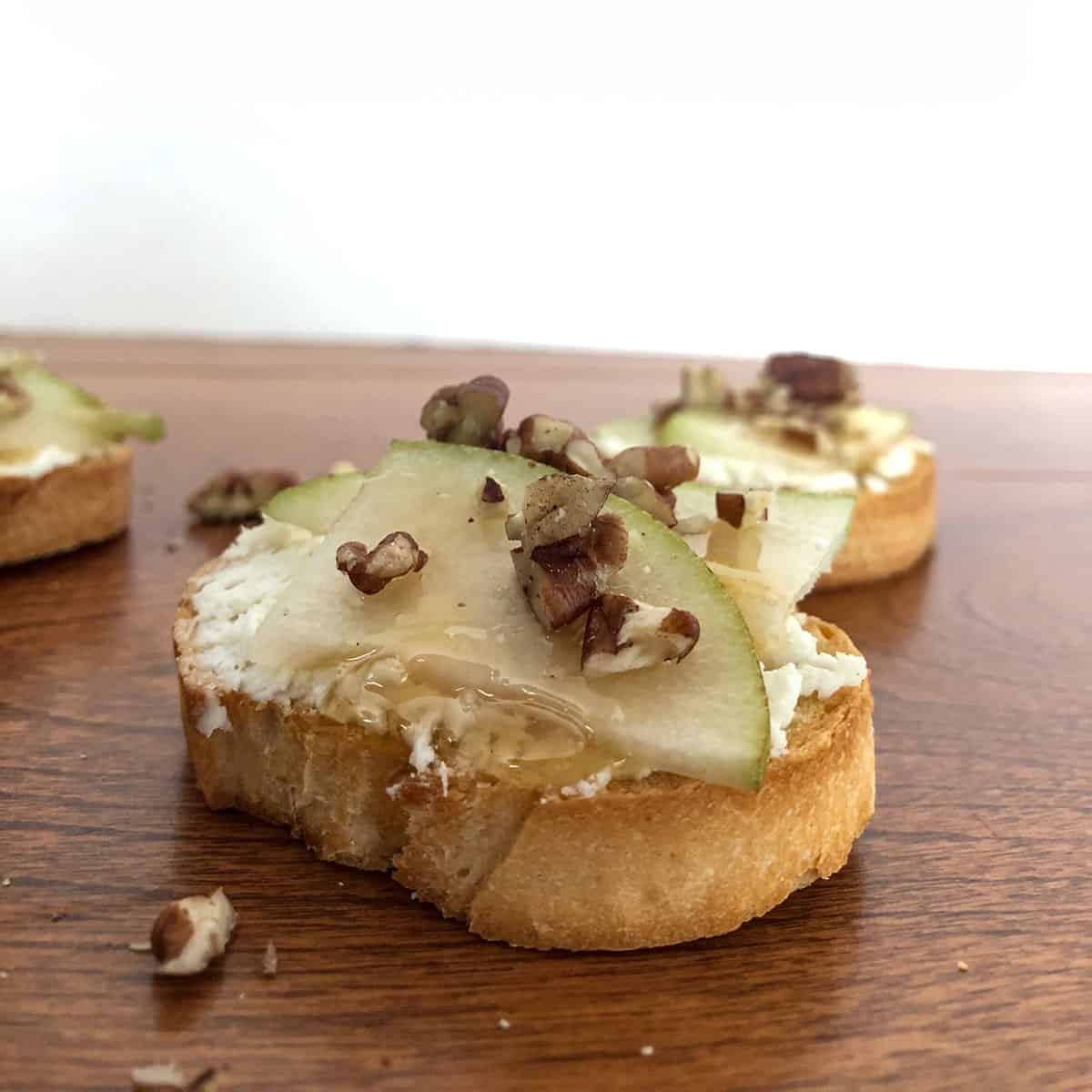 Crostini topped with goat cheese, pear, honey, and pecans.