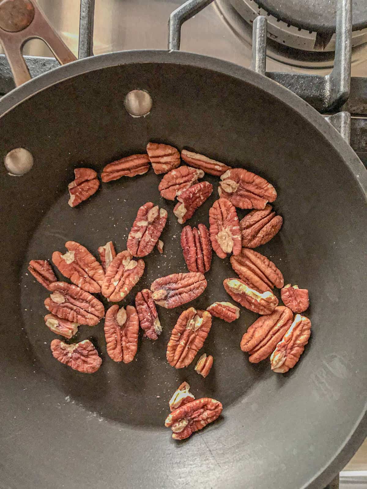 Pecans in a skillet on the stovetop.
