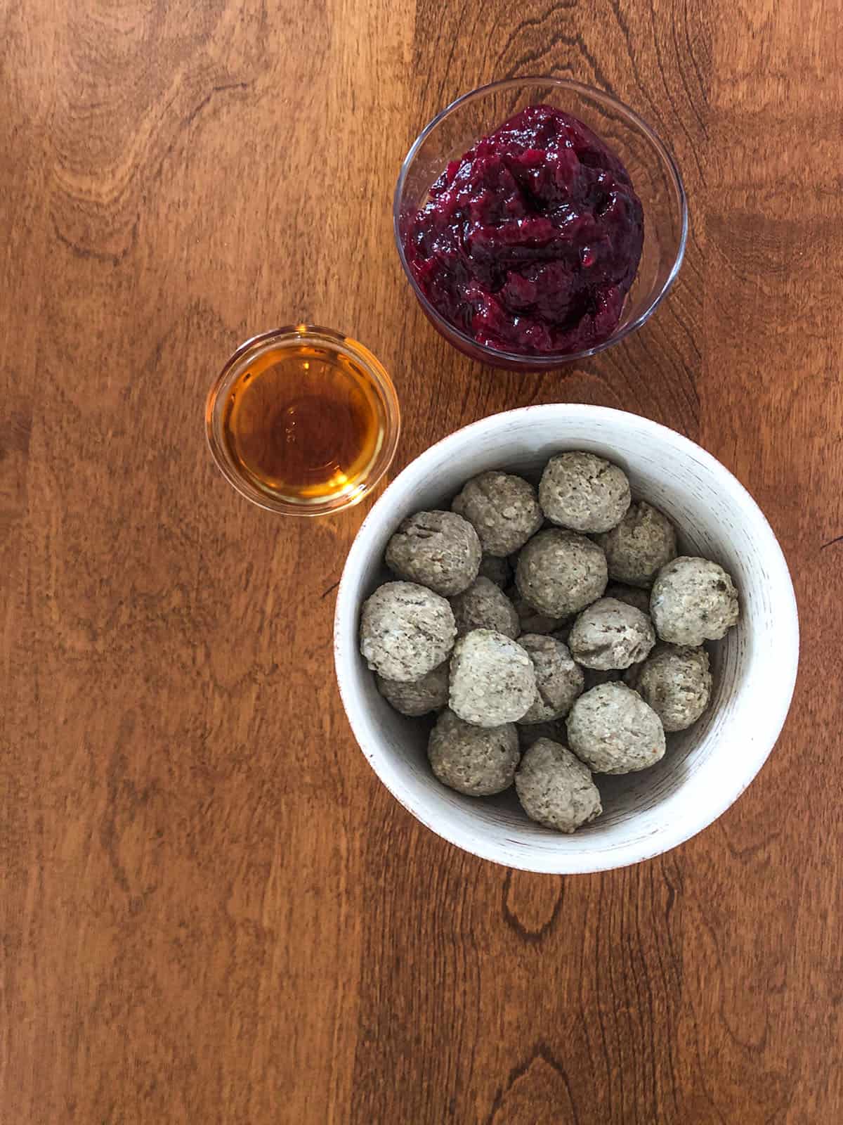 Cocktail meatballs, cranberry sauce, and brandy in individual dishes.