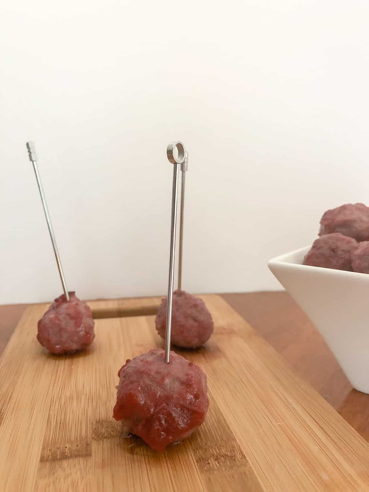 Turkey meatball on a cocktail pick sitting on a wood serving board.