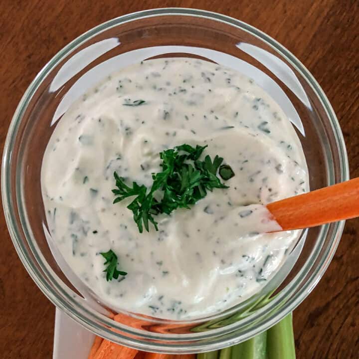 Herb dip in a bowl with carrots and celery.