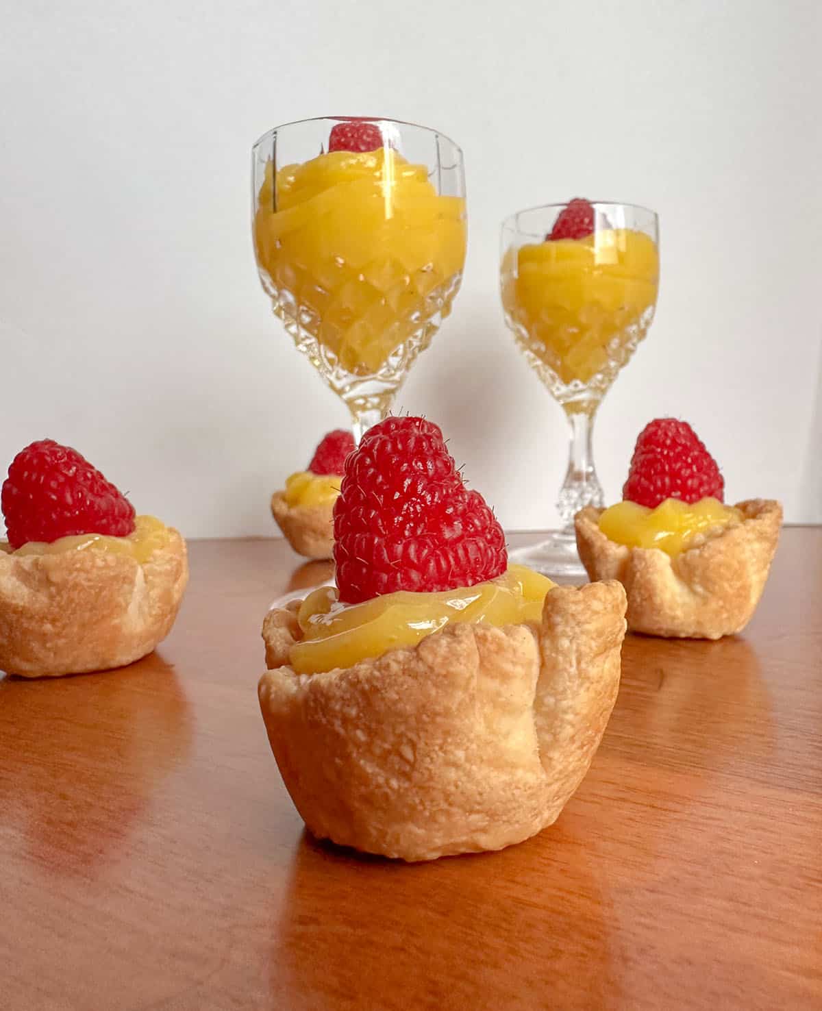 Lemon curd in pie shells and cups topped with raspberries.
