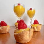 Lemon curd in tartlet shells and cups topped with a raspberry.