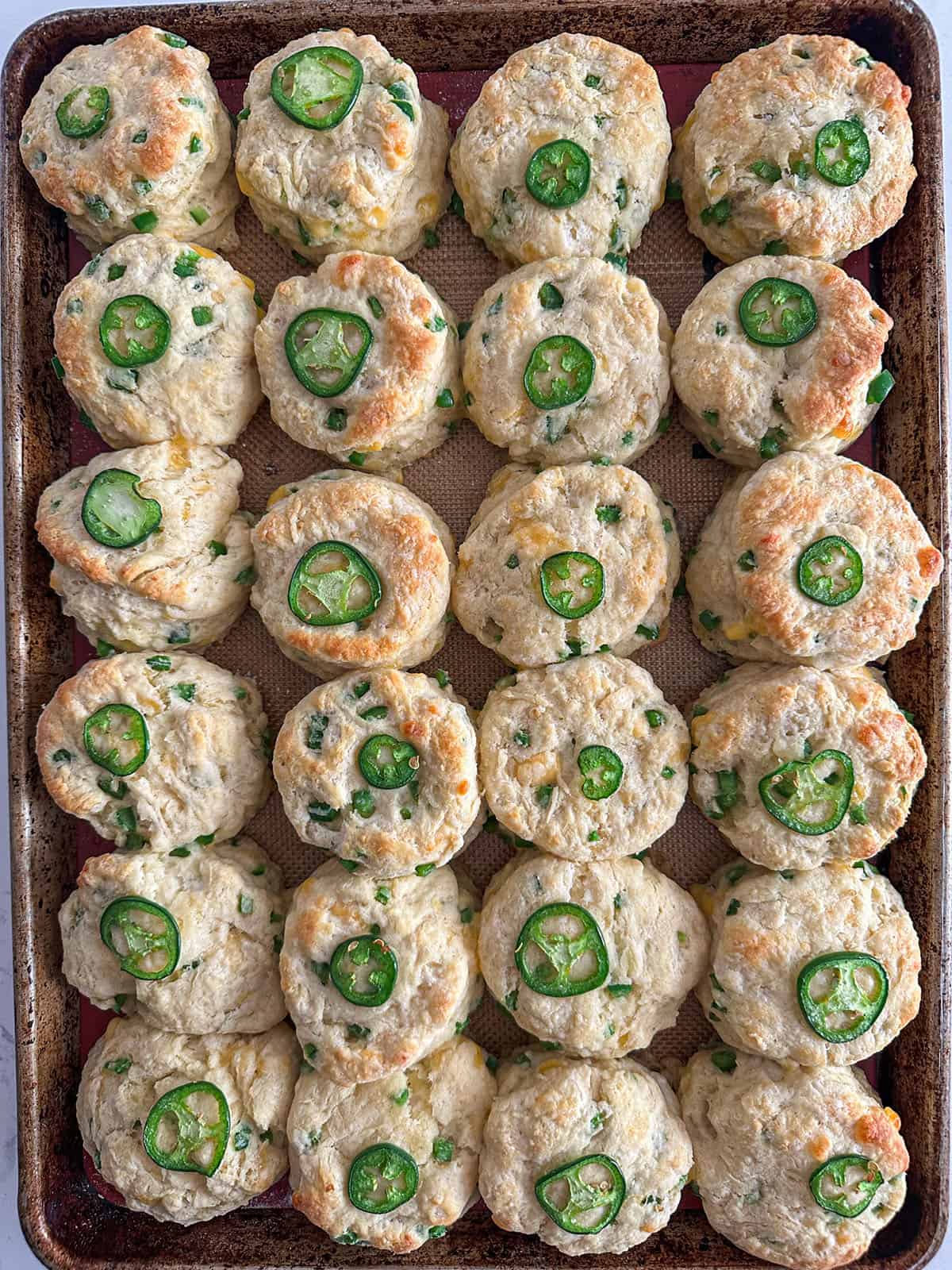 Baked jalapeño cheddar biscuits on a sheet pan.