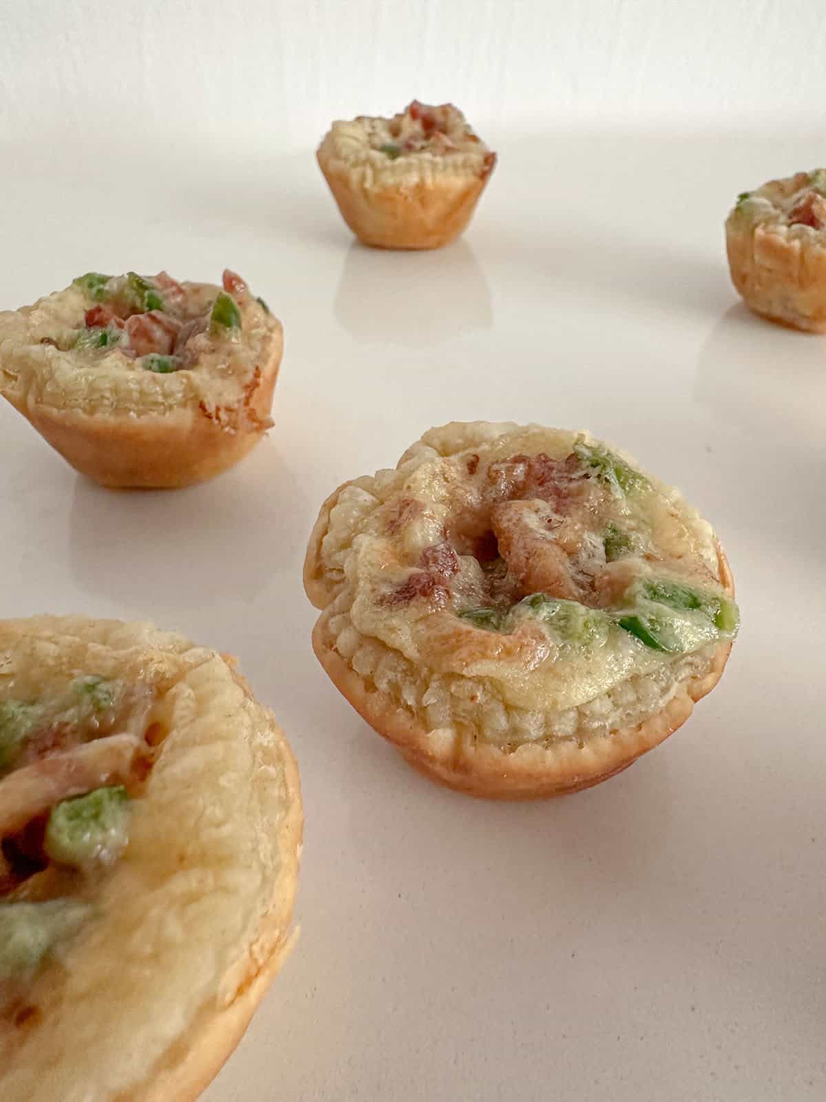 Baked puff pastry jalapeño popper cups on a counter.