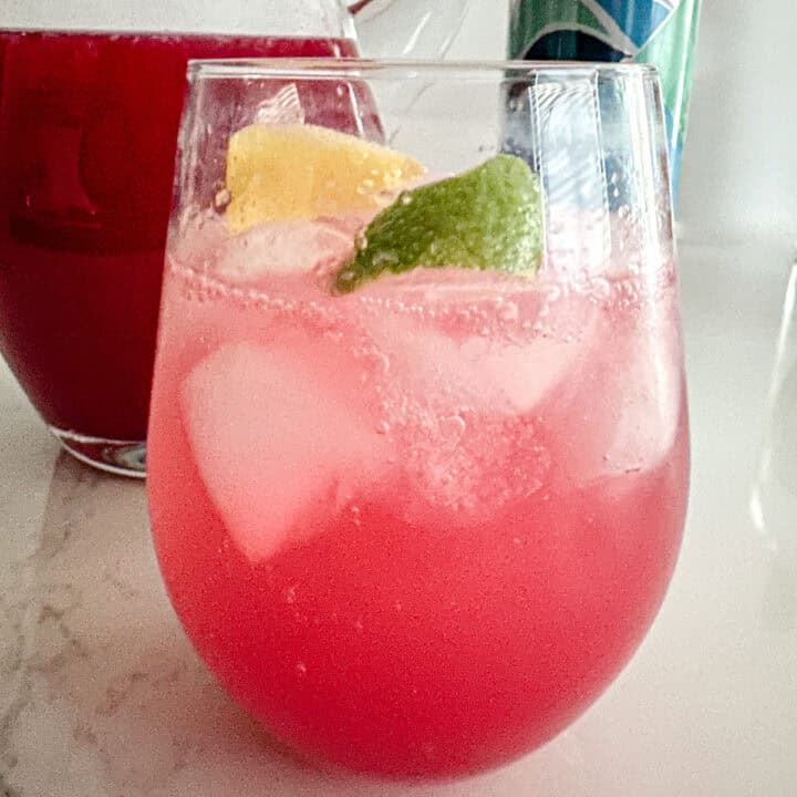 Glass with cranberry simple syrup, lemon and lime juice, and club soda.