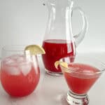 Pitcher of cranberry-citrus mix, a glass with mix and soda, and a glass with mix and whiskey.