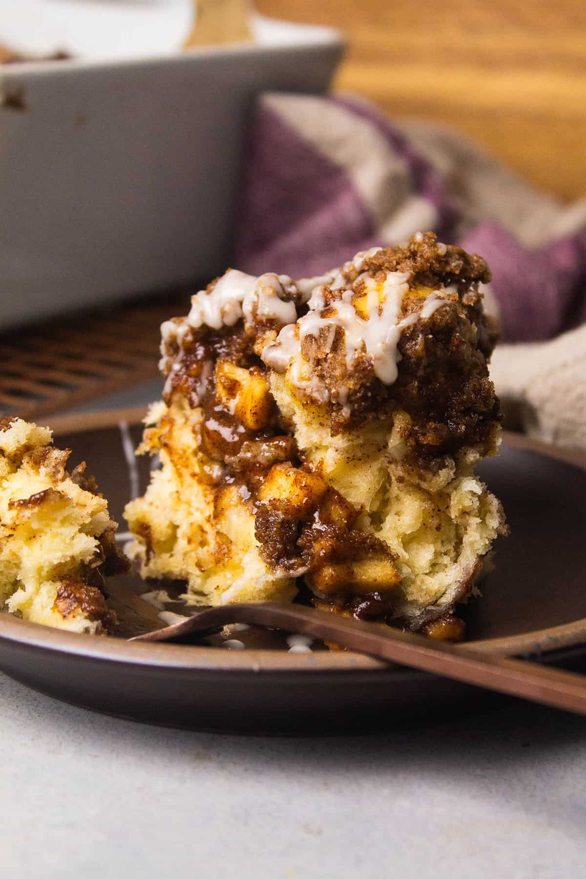 Apple pie cinnamon roll on a plate with a fork.