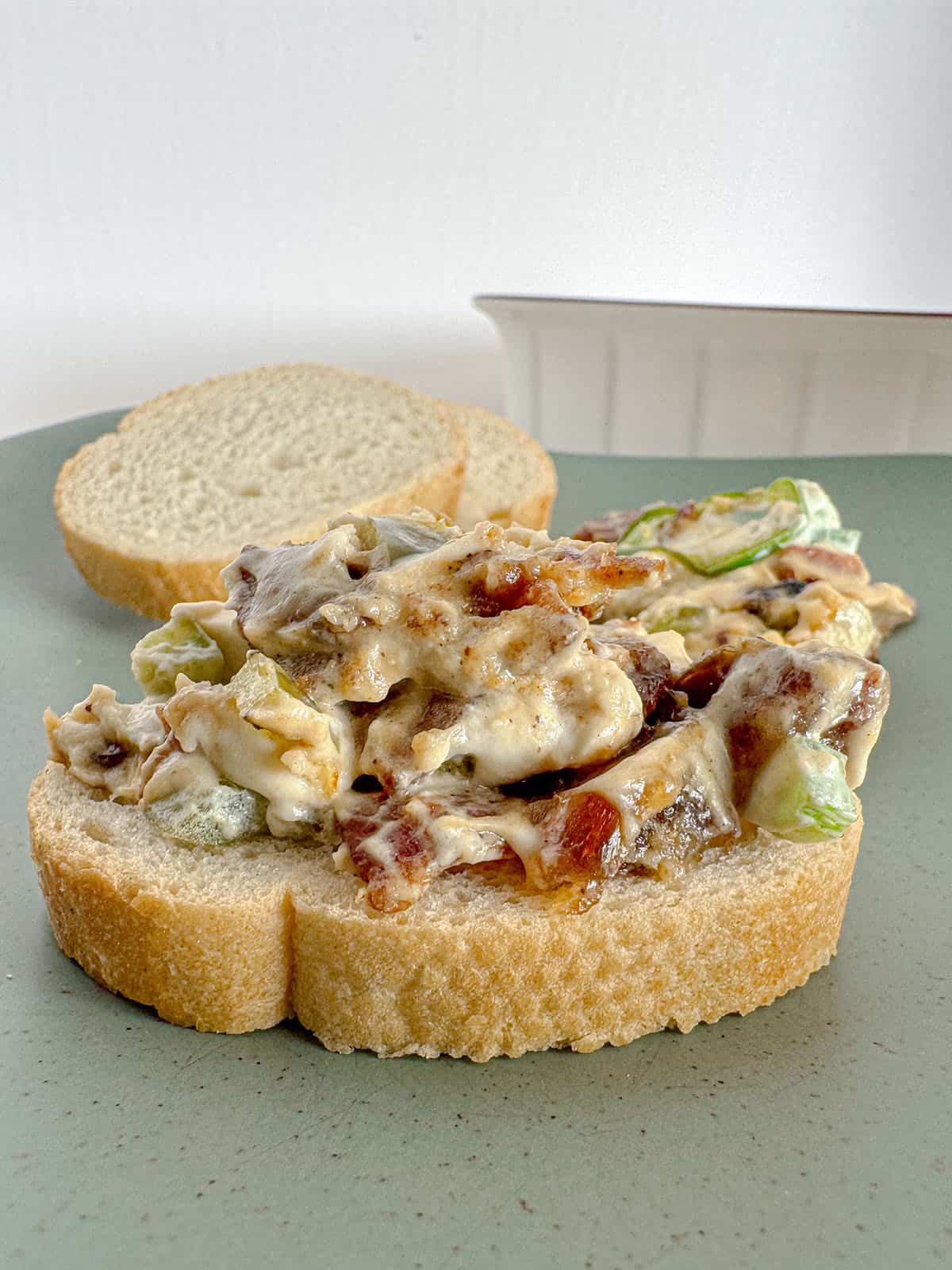 Jalapeño bacon and date dip on sliced baguette on a plate.