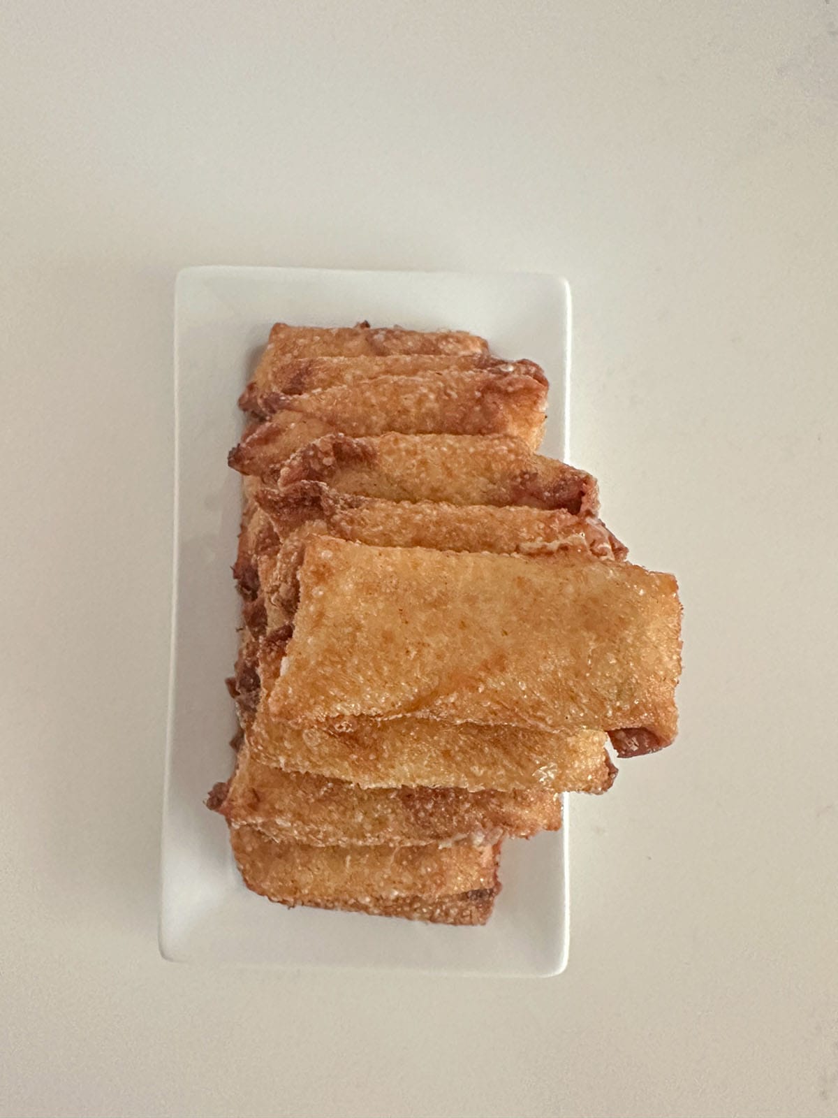 Stacked pyramid of mini crab egg rolls on a plate.