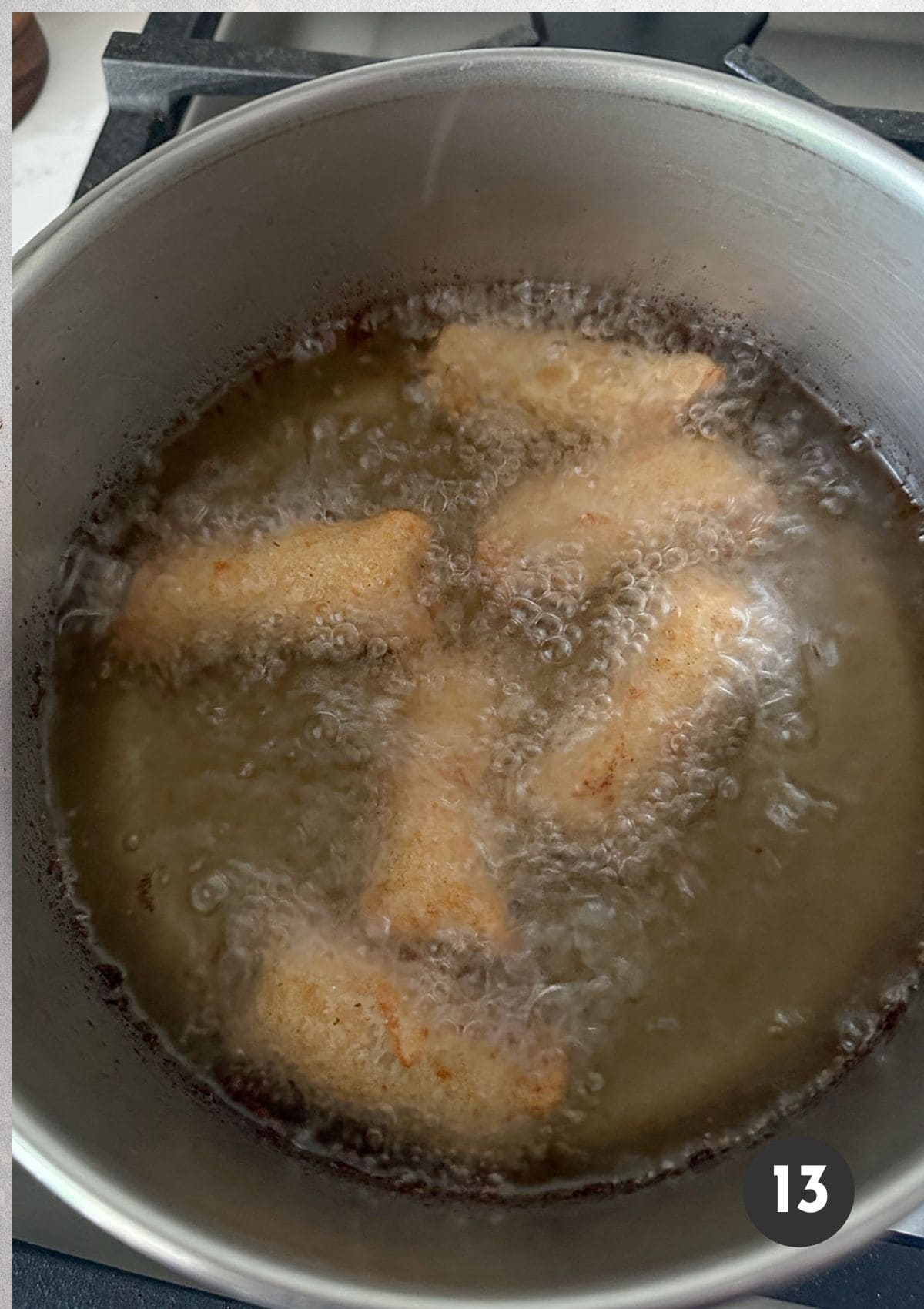 Frying mini crab egg rolls in a pan of hot oil.
