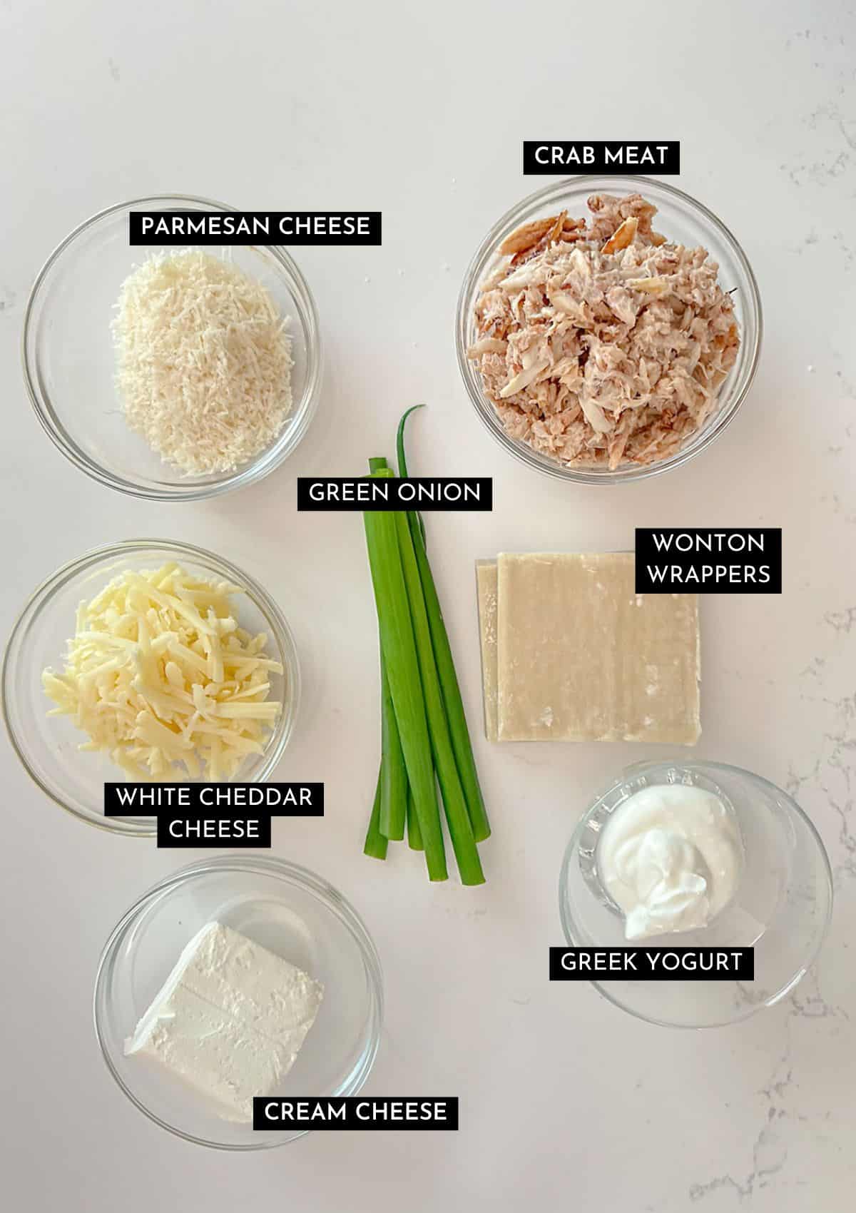 Fresh crab meat, parmesan cheese, green onion, white cheddar cheese, cream cheese, Greek yogurt, and wonton wrappers in individual dishes.