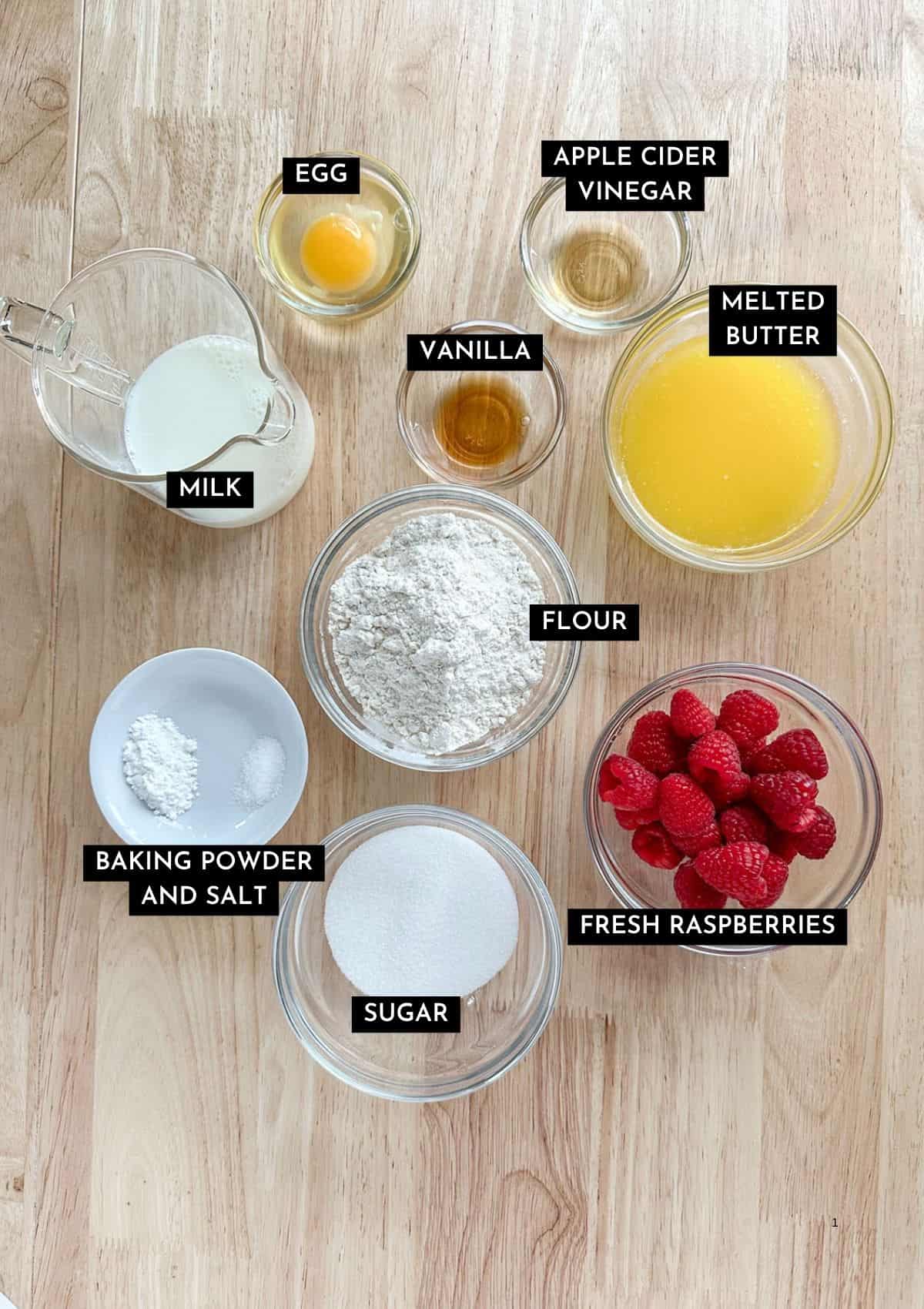 Melted butter, flour, vinegar, vanilla, egg, milk, sugar, baking powder, salt, and fresh raspberries in individual dishes.