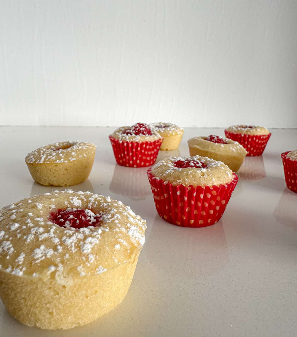 Powdered sugar dusted mini raspberry muffins on a table.