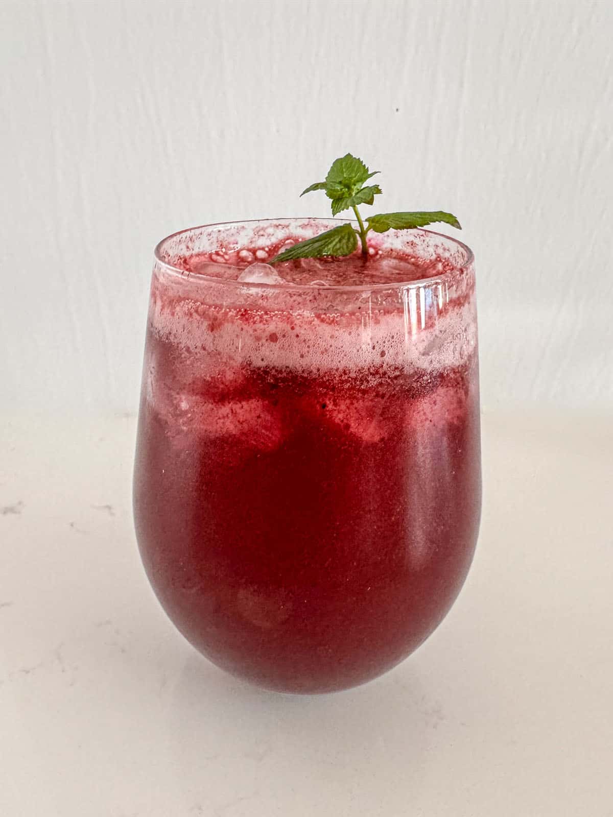 Glass with red beverage and mint sprig.