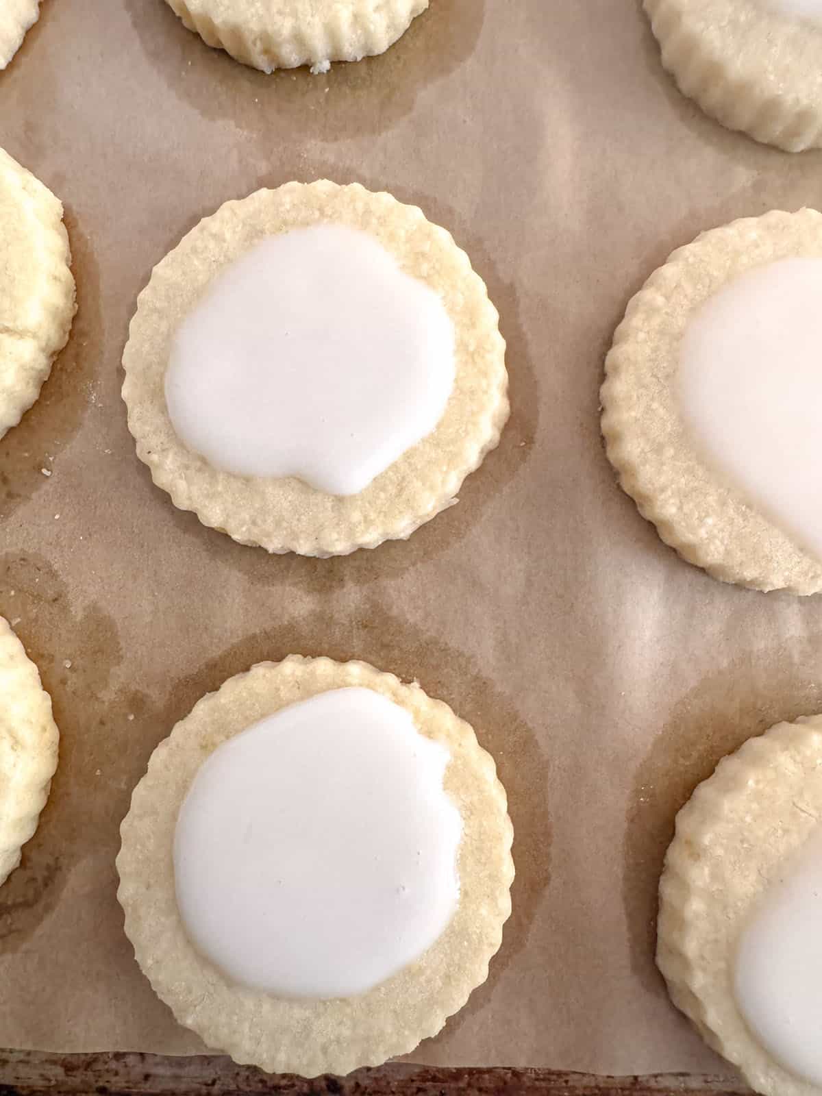 Iced lemon shortbread cookies on parchment paper.
