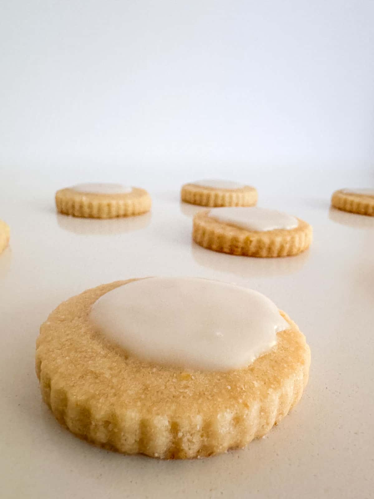 Iced lemon shortbread cookies scattered on table.