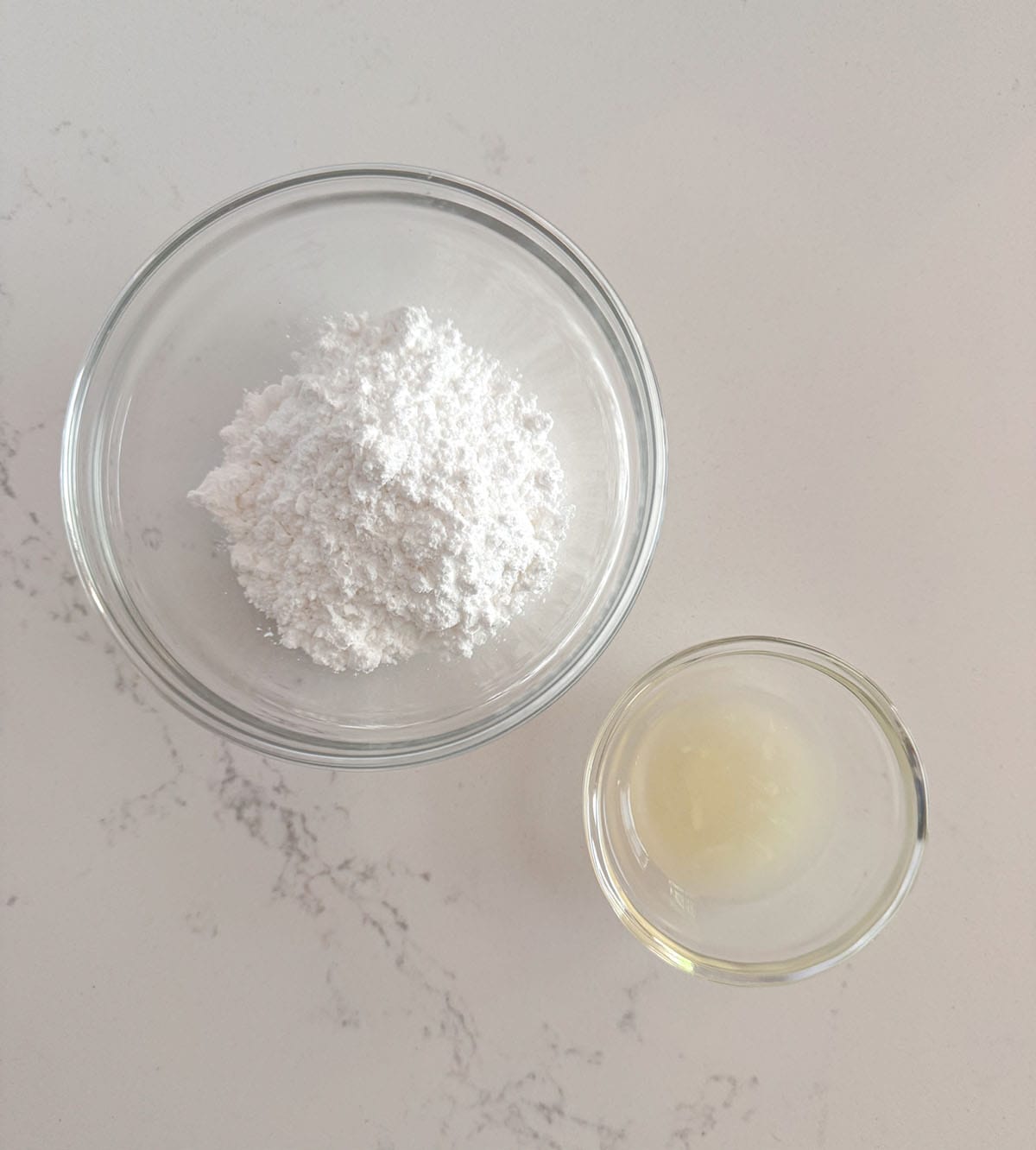 Powdered sugar and lemon juice for lemon glaze in individual bowls.